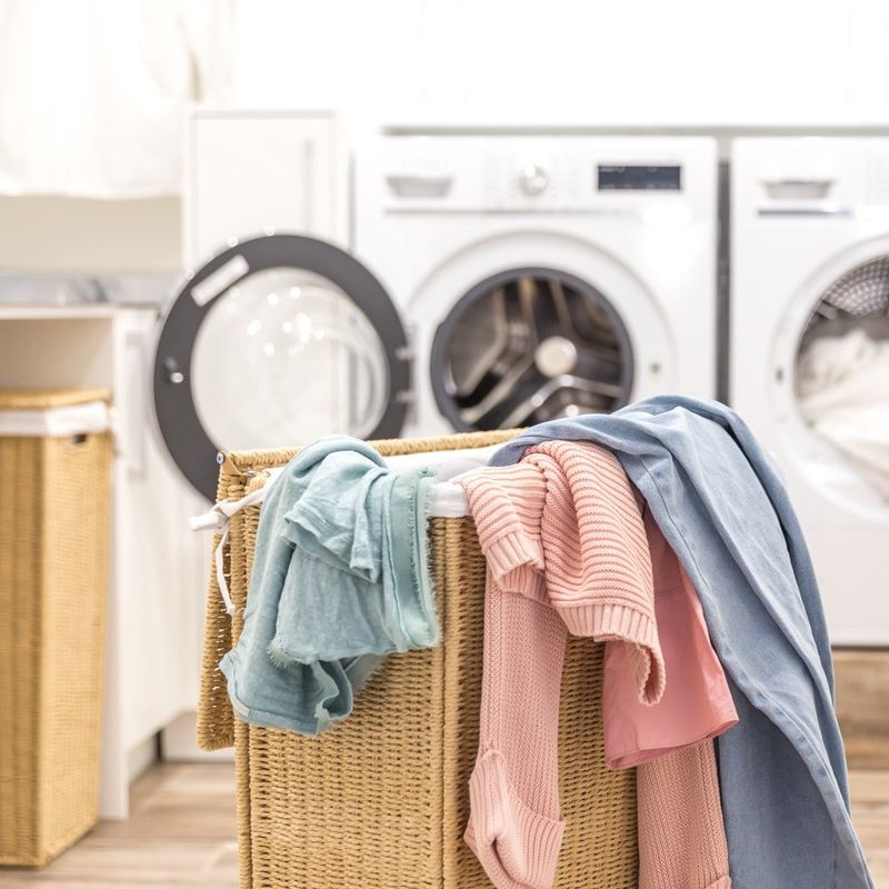 cesto de ropa sucia con lavadoras desenfocadas de fondo